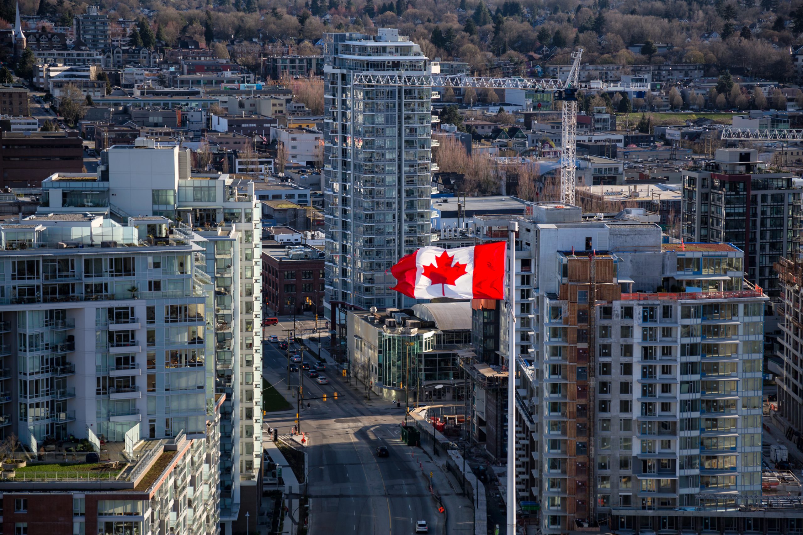 Aerial view of a Canadian Flag Flapping in the Wind with buildings in background